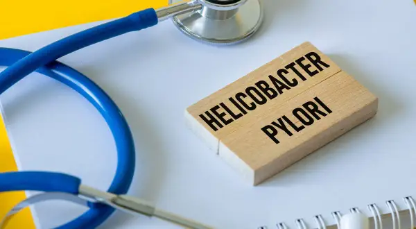 Stetoskop i klocki z napisem "Helicobacter pylori" symbolizują problemy zdrowotne, w tym potencjalne helicobacter pylori objawy psychiczne.