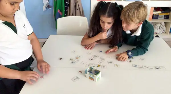 Niños concentrados en juegos de verbos con tarjetas de imágenes.