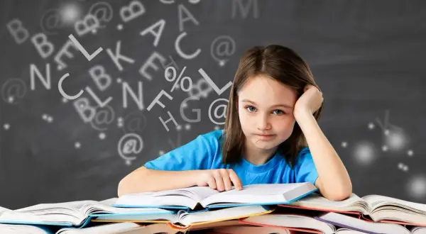 Een meisje met een vermoeide blik zit achter een stapel boeken, omringd door zwevende letters. Ze heeft duidelijk moeite met begrijpend lezen.