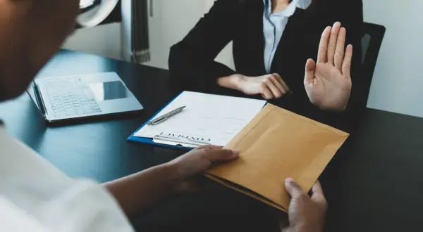 Une main tend une enveloppe, l'autre la refuse. Une scène évoquant le délai réponse inspection du travail licenciement salarié protégé.