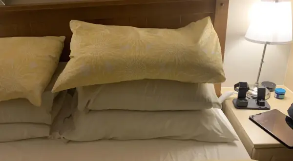 A stack of three pillows, one with a yellow sunflower pattern, sits on a bed. Perfect for sleeping with 3 pillows for ultimate comfort.
