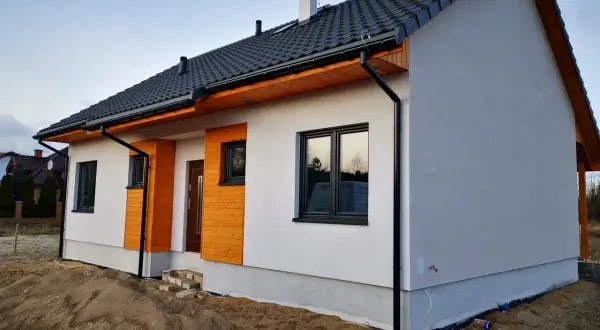 Nowoczesne domy szkieletowe na zgłoszenie, białe z drewnianymi elementami, gotowe do zamieszkania.