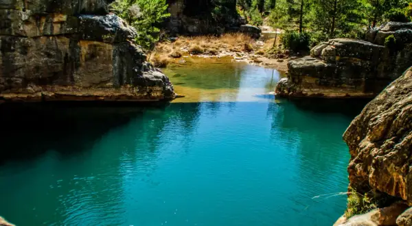 Aguas turquesas de ríos cerca de Zaragoza, rodeadas de rocas y vegetación exuberante. Un rincón natural para descubrir.