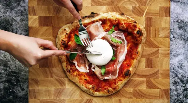 Une pizza burrata avec du prosciutto et du basilic, prête à être dégustée.