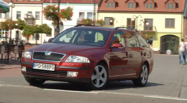 Czerwona Skoda Octavia 2 kombi na ulicy, z widocznymi żarówkami w przednich reflektorach.