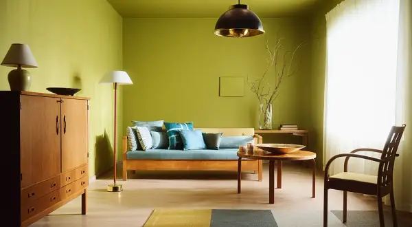 Zielone kolory ścian inspiracje: salon z drewnianą komodą, kanapą i krzesłem.