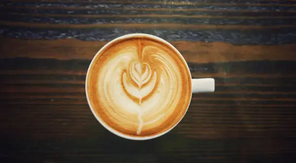 A filiżanka kawy latte z pięknym wzorem na piance. Czy kawa podnosi ciśnienie? Ta pyszna kawa na pewno podniesie Ci nastrój!