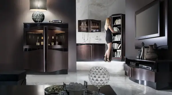 Elegancki salon z meblami w kolorze wenge. Kobieta w czarnej sukience wybiera książkę z regału.