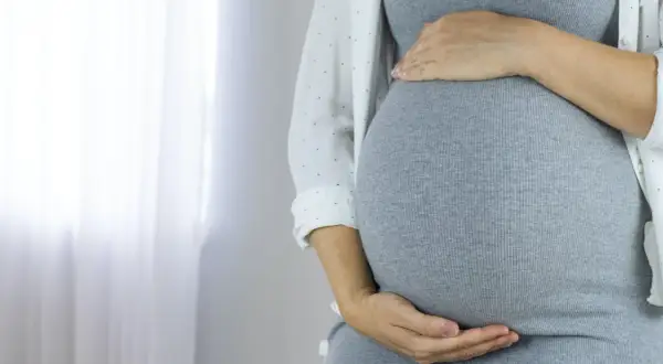 Kobieta w ciąży z dłońmi na brzuchu. Może to być związane z cholestazą ciążową.