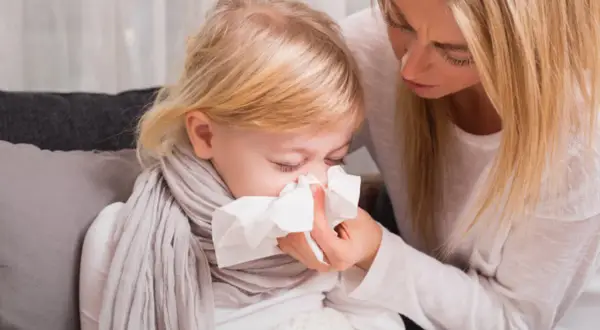 Mama troszczy się o dziecko z zielonym katarem, podając mu chusteczkę.