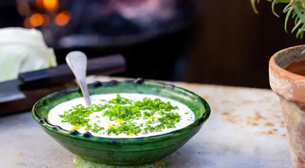 Grönskande skål med krämig ranch dressing, toppad med färska örter. En sked vilar i skålen, redo att servera.