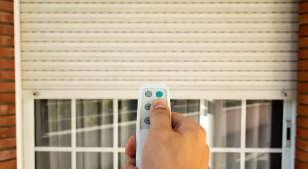 Mano che usa un telecomando per alzare una tapparella elettrica. Utile per capire quanto costa mettere le tapparelle elettriche.