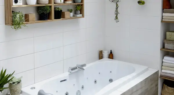 Baignoire d'angle avec robinetterie chromée. La hauteur du robinet baignoire est idéale pour remplir la vasque. Des plantes décorent l'espace.