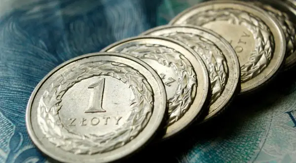 Rząd polskich monet 1 złoty na tle banknotu. Marzenie o 6000 brutto zaczyna się od oszczędzania.