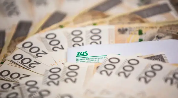Stos banknotów 200 zł z logo ZUS. Mały zus i dużo pieniędzy.