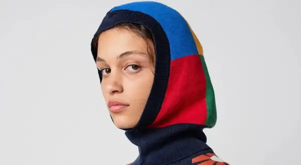 Mujer con balaclava que es una prenda de punto multicolor, con bloques de azul, rojo, amarillo y verde.