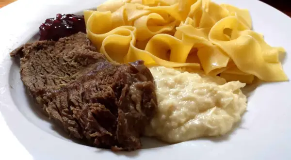 Ein Teller mit deftigem Braten, Bandnudeln, Klößen und Preiselbeeren – ein typisches Hochzeitsessen in Franken.