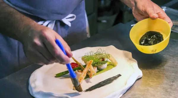 Szef kuchni w restauracji z gwiazdką Michelin precyzyjnie dekoruje danie.