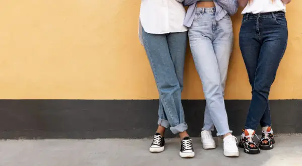 Trzy dziewczyny w szerokich jeansach i modnych sneakersach. Idealne inspiracje, jakie buty do szerokich spodni jeansowych.