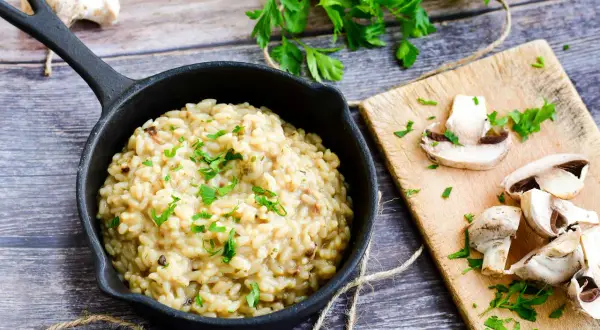 Kremowe włoskie risotto z grzybami, posypane natką pietruszki. Idealny przepis na pyszny obiad.