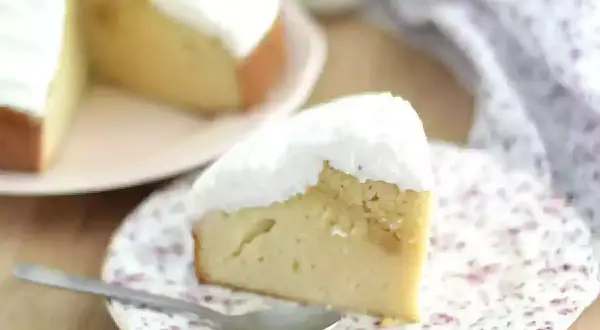 En saftig bit tres leches-kaka med fluffig vit topping, serverad på en blommig tallrik med en sked.