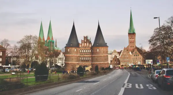 Holstentor, en ikonisk portbyggnad i norra Tyskland, med sina karaktäristiska torn och kyrkor i bakgrunden.
