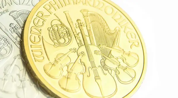 Złota moneta z instrumentami muzycznymi, w tym skrzypcami i harfą. Napis "Wiener Philharmoniker" otacza scenę.