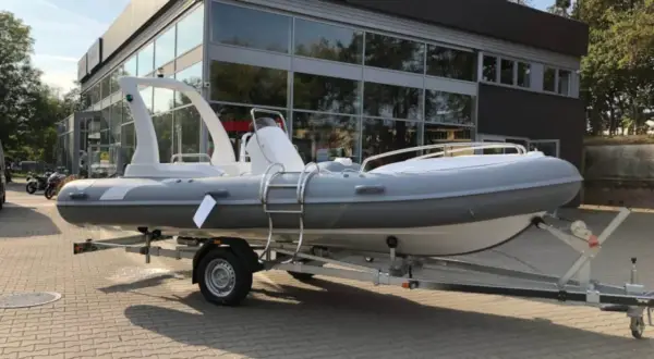 Szara łódź typu RIB na przyczepie przed budynkiem z logo Yamaha.