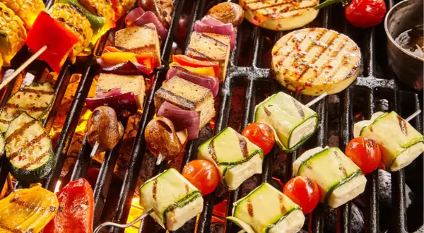 Bunte Spieße mit Tofu, Zucchini, Tomaten, Mais und Paprika brutzeln auf dem Grill. Ein Genuss für vegetarisches Grillen!