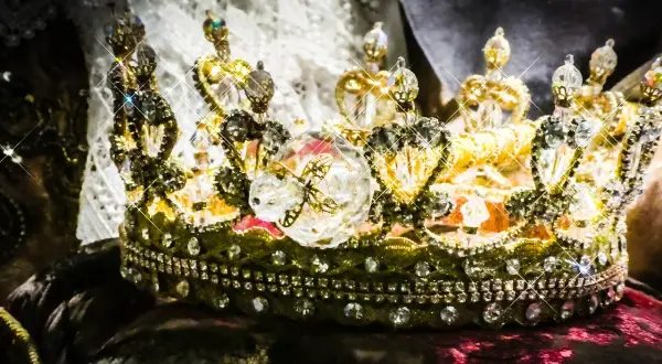 Korona zdobiona klejnotami, symbol bogactwa i władzy, przypomina o globalnym wydobyciu złota.