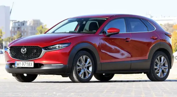 Czerwona Mazda CX-30 z polskimi tablicami rejestracyjnymi stoi na zewnątrz.