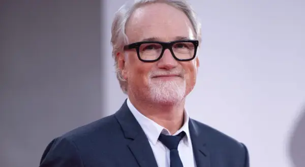 David Fincher, reżyser znany z mrocznych i wciągających filmów, w eleganckim garniturze i okularach.