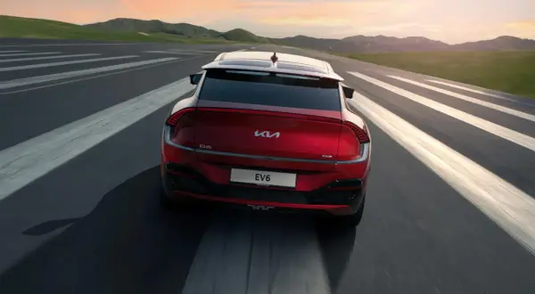 Röd Kia EV6 kör på en väg med vita linjer. En besiktning av spindelleder kan vara aktuell om det finns glapp.
