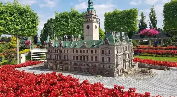 Miniaturowy ratusz i wieża z zegarem otoczone czerwonymi kwiatami. Idealne kotlina kłodzka atrakcje dla dzieci.