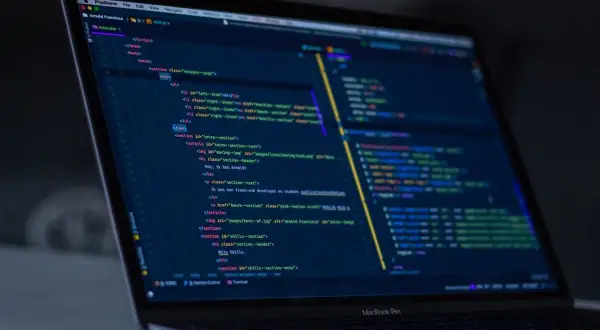 Code sur un écran d'ordinateur portable, affichant du code HTML et JavaScript, avec des éléments de développement web, comme un `EventEmitter` dans Angular.