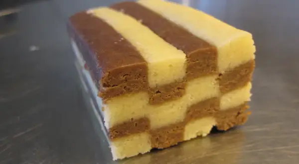 En bit av ett hembakat schackrutemönstrat kex med choklad och vaniljsmak.