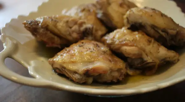 Un plat de haut de cuisse de poulet rôti, assaisonné d'herbes, servi sur une assiette en céramique crème.