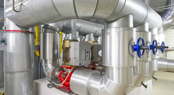 Detailaufnahme einer Anlage mit großen Rohren, Pumpen und Ventilen, die an ein mini blockheizkraftwerk angeschlossen sind.