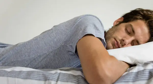 Hombre durmiendo boca abajo, con la cabeza apoyada en una almohada. Se pregunta: "porque sudo mucho cuando duermo soy hombre".