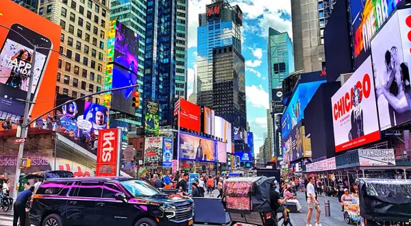 Times Square w Nowym Jorku z neonami, ludźmi i rikszami.