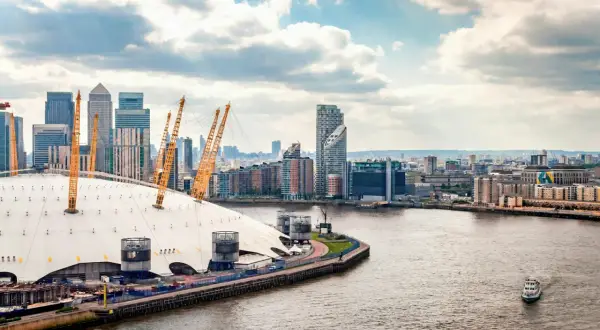 En linbana London över Themsen, med O2 Arena och skyskrapor i bakgrunden.