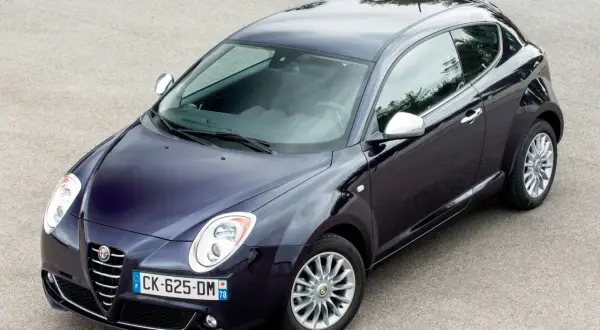 Elegancki, granatowy Alfa Romeo MiTo na tle asfaltu. Wiele osób szuka alfa romeo mito opinie, by poznać ten model.