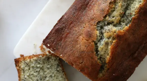 Un délicieux cake citron pavot, doré et moelleux, avec une tranche coupée. Parfait pour le goûter.