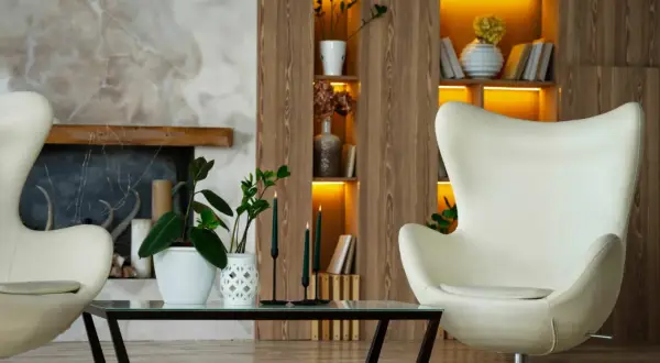 Gemütliches Wohnzimmer mit zwei weißen Eier-Sesseln, einem Couchtisch mit Pflanzen und Kerzen, Kamin und einem Regal im **mid century design**.