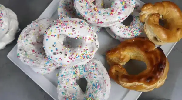 Biscotti a ciambella con glassa bianca e zuccherini colorati, pronti per essere gustati. La glassa per biscotti che si asciuga subito li rende perfetti.