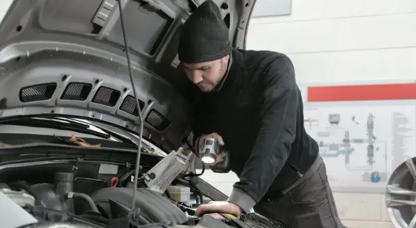 Mechanik z latarką bada silnik 1.9 TDI.