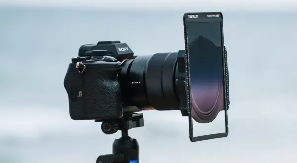 Aparat Sony z obiektywem i uchwytem na filtry do zdjęć. Tło rozmyte, morskie.