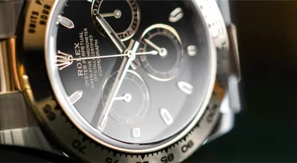 Primer plano de un Rolex Daytona con esfera negra y cristal hesalite. Los detalles del cronógrafo y la inscripción son visibles.