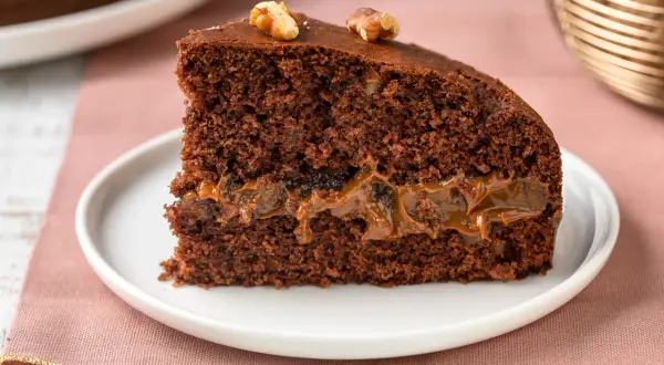 Una fetta di torta al cioccolato con ripieno di caramello e noci, perfetta tra i dolci per le feste.