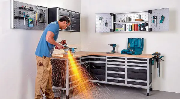 Un homme utilise une meuleuse d'angle dans son atelier bien rangé, créant un spectacle d'étincelles vives.